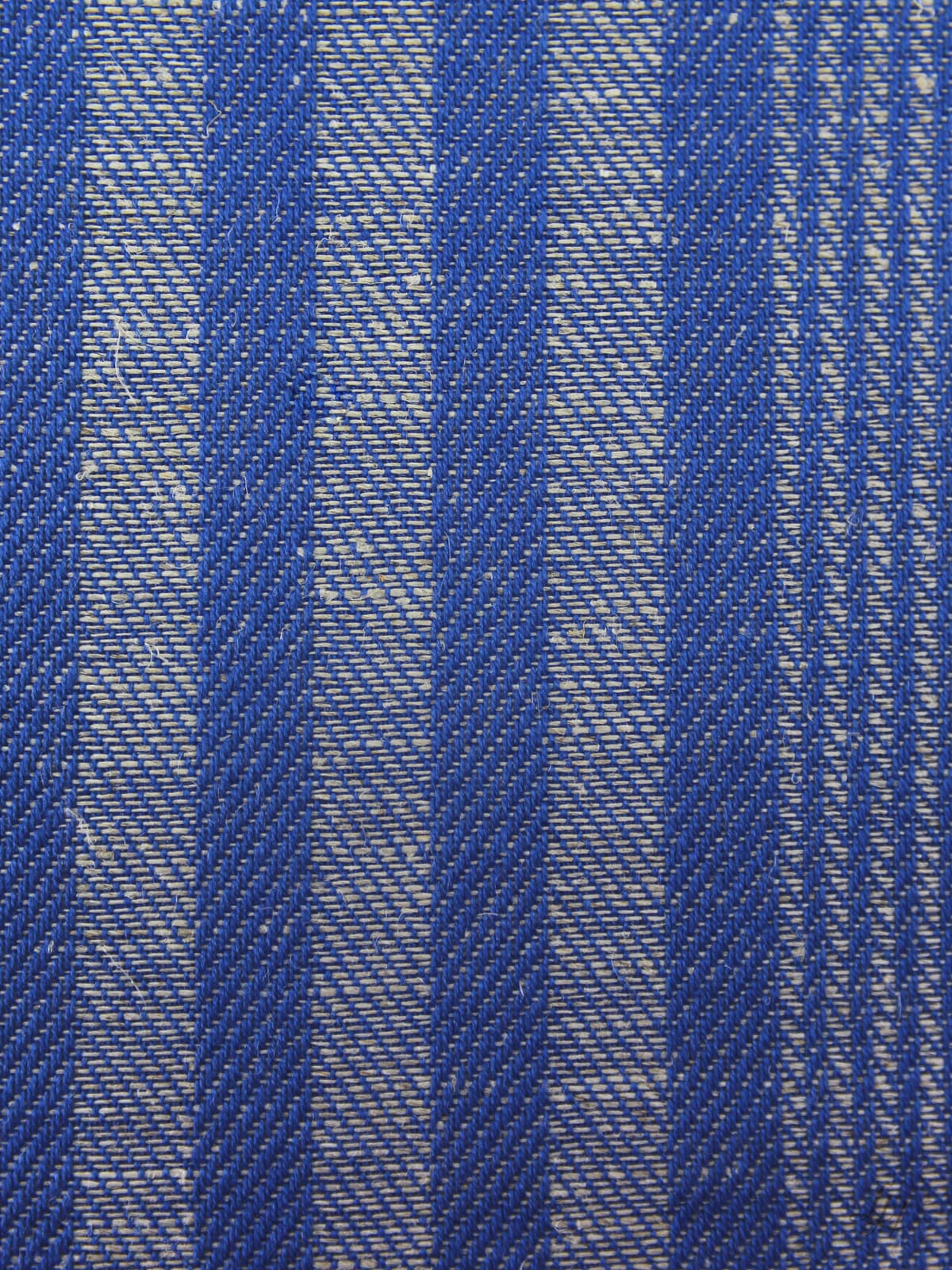 Nahaufnahme von blauen und weißen Streifen auf einem strukturierten Leinen-Grubentuch, die diagonale Linien im gewebten Fadenmuster zeigen.