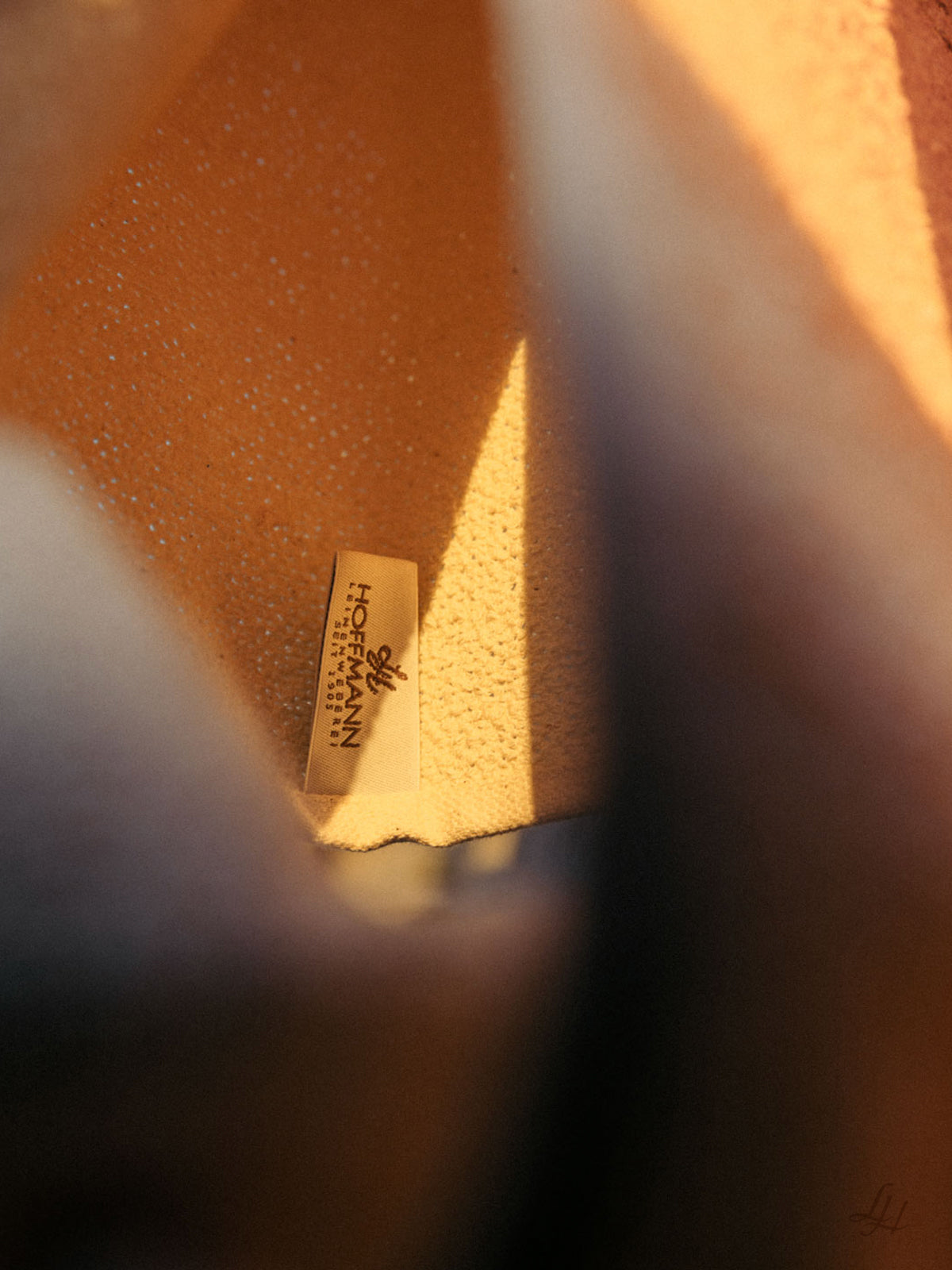 Eine Nahaufnahme einer hellbraunen Veloursleder-Innenausstattung mit einem Högl Höfmann-Label, daneben ein weiches Leinenhandtuch für optimale Hautpflege.