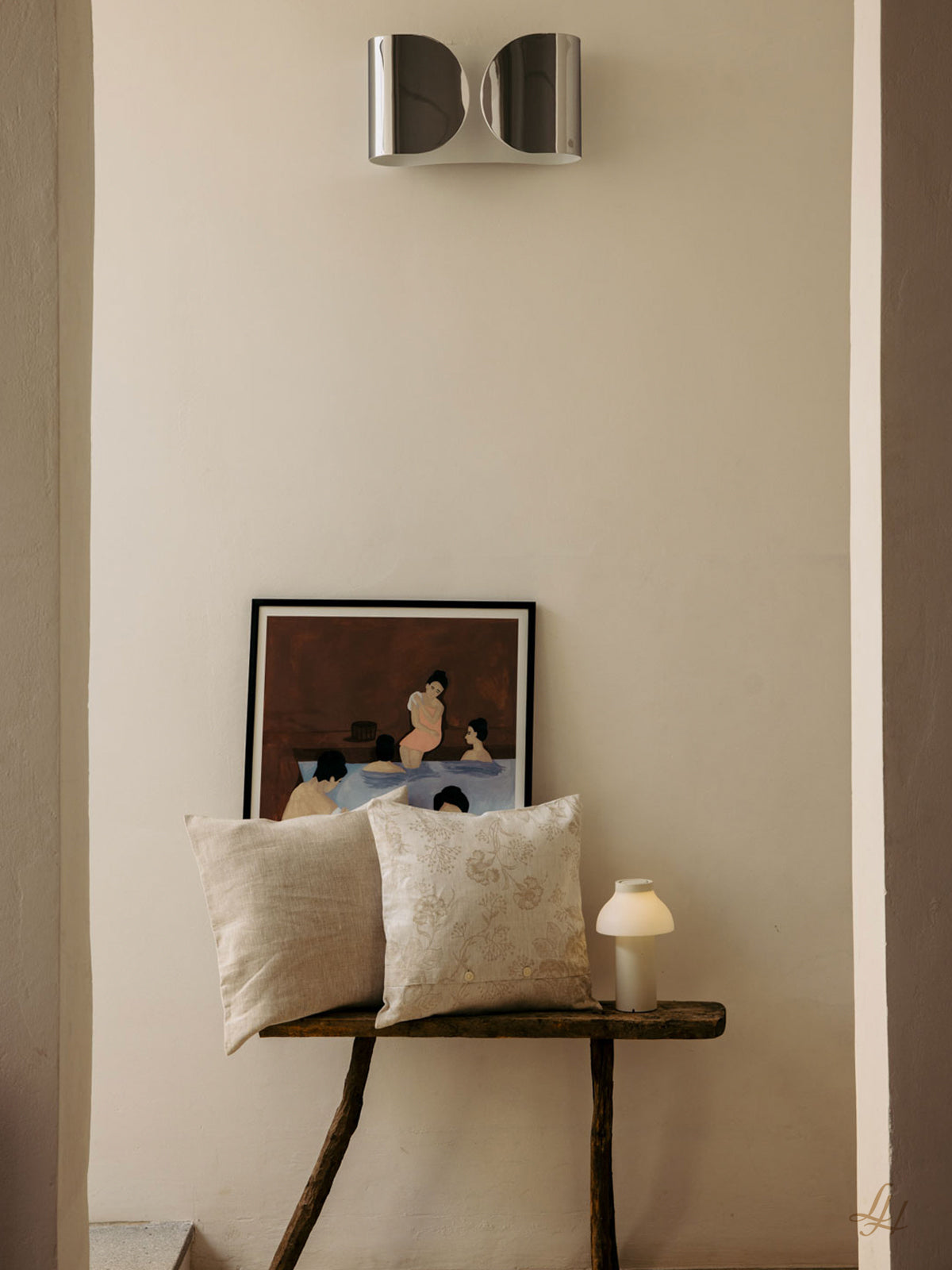Eine rustikale Holzbank mit hypoallergenen Leinen-Kissenbezügen, eine Lampe und ein Bild unter einer modernen Leuchte.