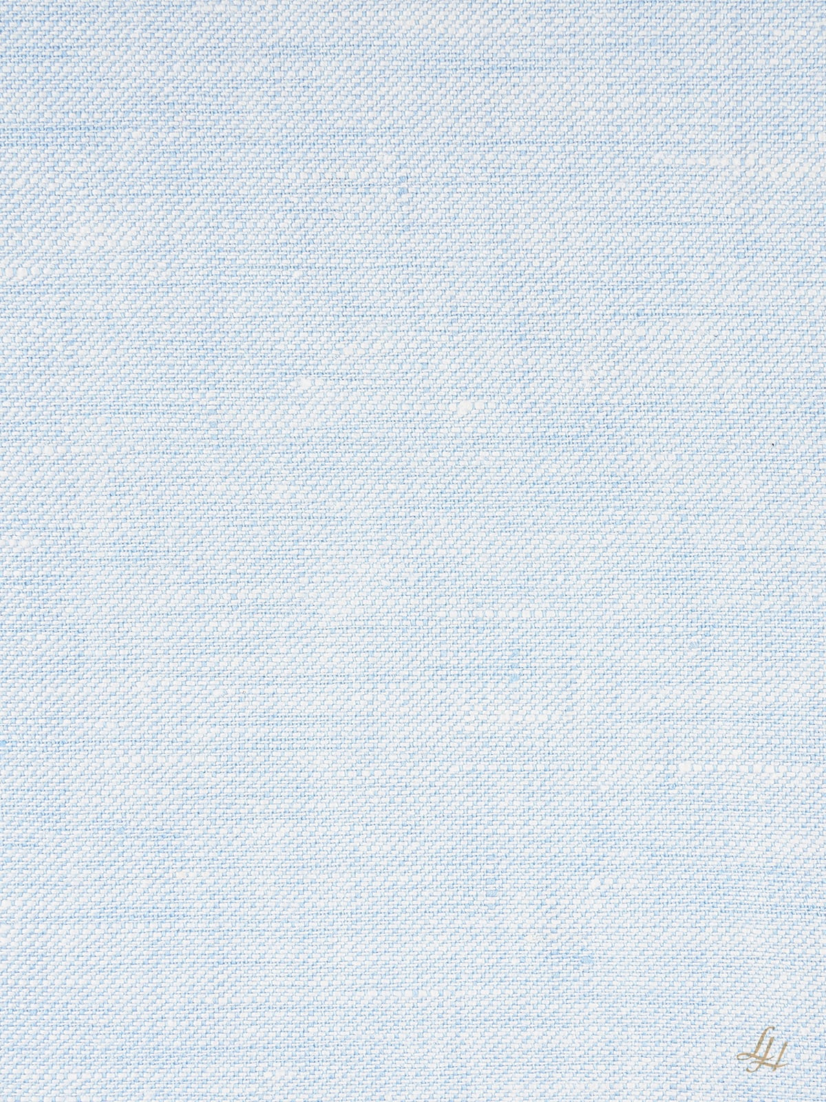 Ein hellblauer, mit Köperbindung strukturierter Stoffhintergrund mit einem kleinen goldenen Monogramm in der rechten unteren Ecke.