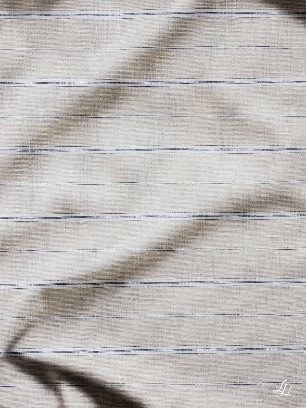 Hellbeige Bettbezug Streifen mit dünnen blauen Streifen und dezenten Schatten; kleines L-Logo in der Ecke.