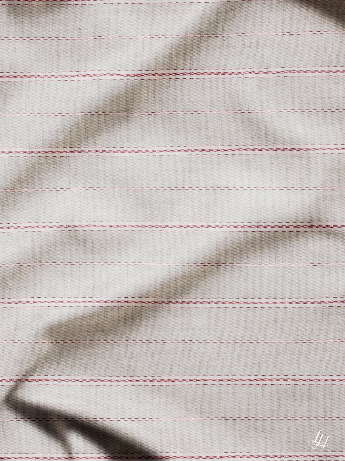 Hellbeige Bettbezug Streifen mit dünnen roten Streifen und sichtbaren Falten; ein kleines weißes Logo befindet sich in der rechten unteren Ecke.