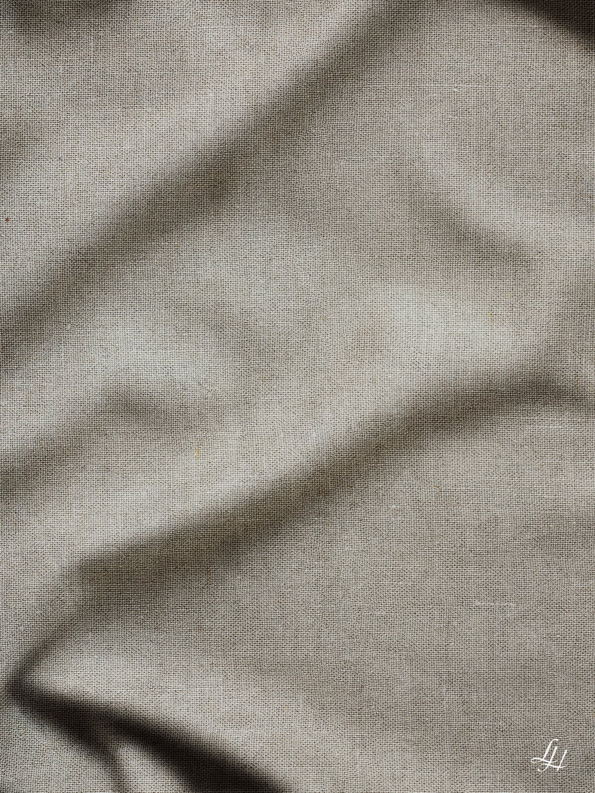 Eine Nahaufnahme von nachhaltigem Leinentuch mit sichtbarer Textur und subtilen Falten, die weiche Schatten erzeugen.