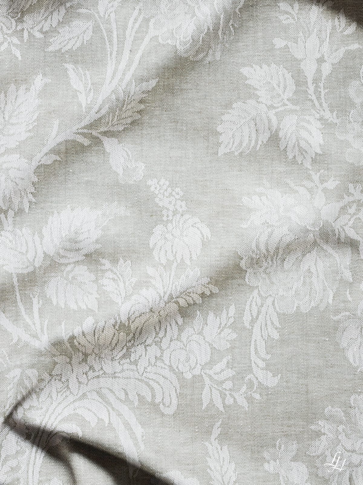 Blumen- und Blätterjacquard aus Chrysantheme Salbei (Dunkel) auf hellgrauem Leinen, mit sichtbarer Struktur und natürlichen Falten.