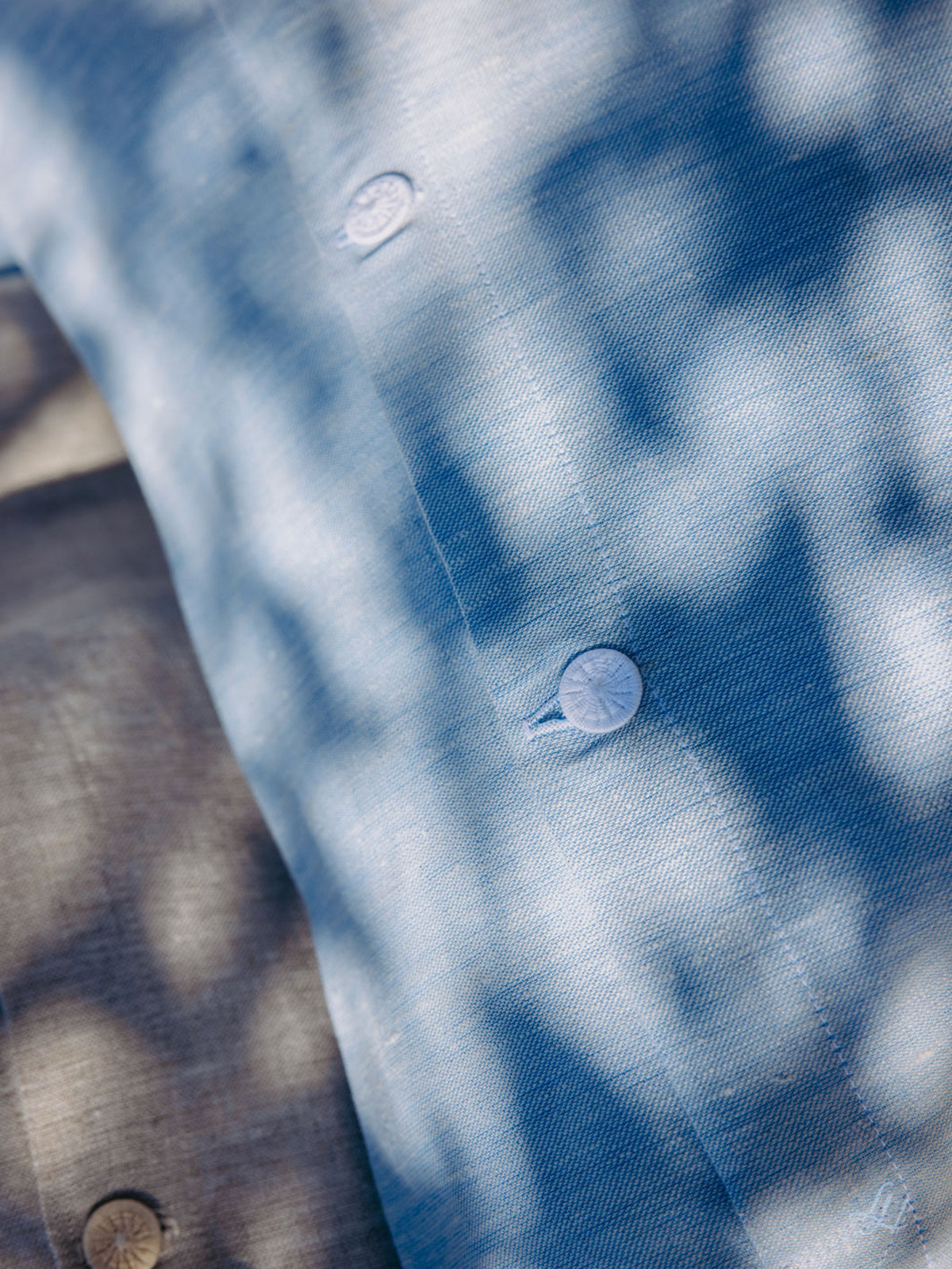 Nahaufnahme eines hellblauen Button-up-Hemdes im Sonnenlicht, gefertigt aus hypoallergenem europäischem Leinen für atmungsaktiven Komfort.