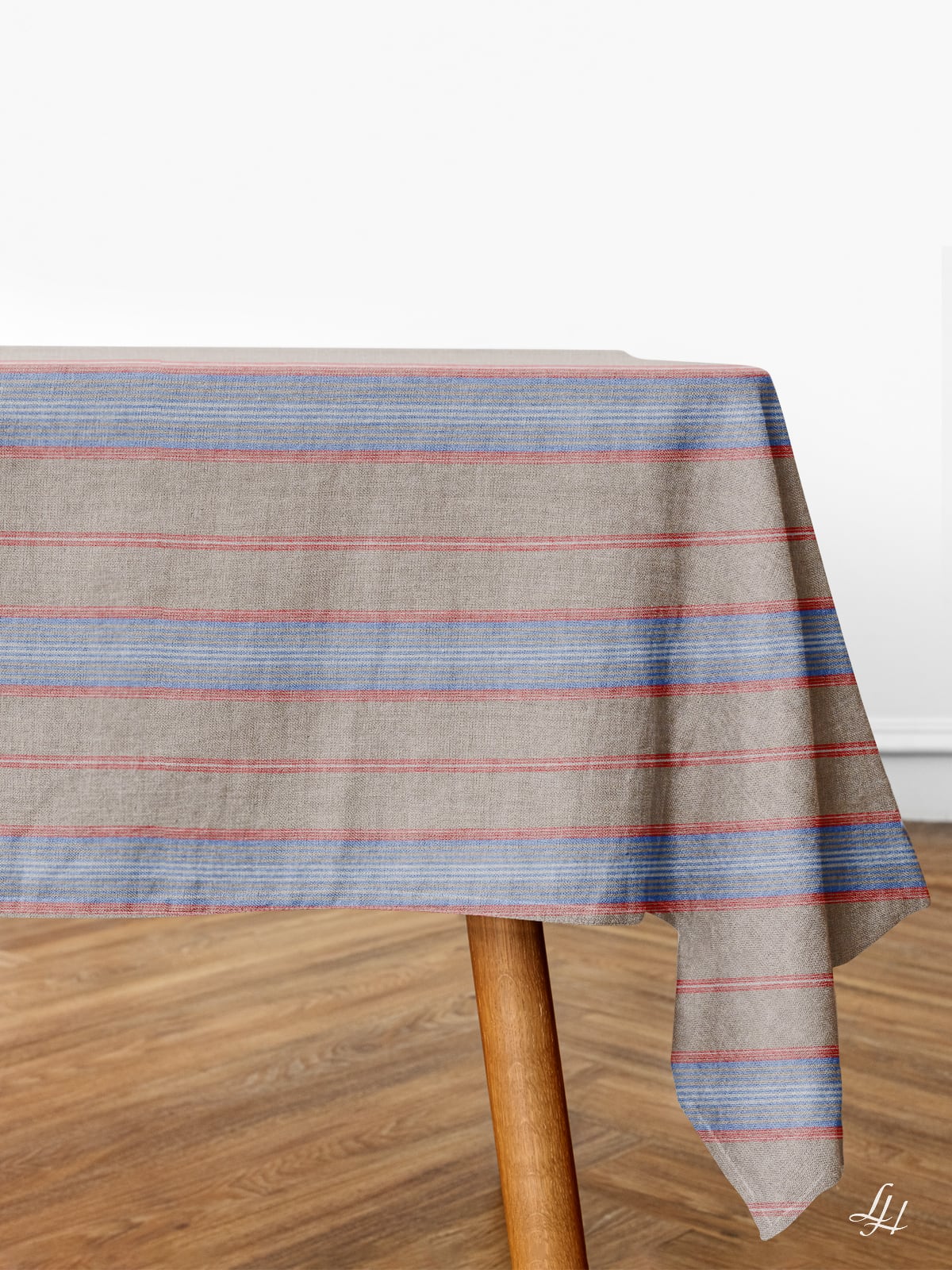 Ein Tisch mit Reinleinen Tischwäsche in blauen und roten Streifen auf einem Holzboden vor einem schlichten weißen Hintergrund.